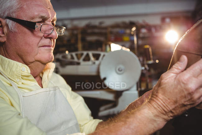 Thoughtful shoemaker examining a shoe in workshop — Stock Photo