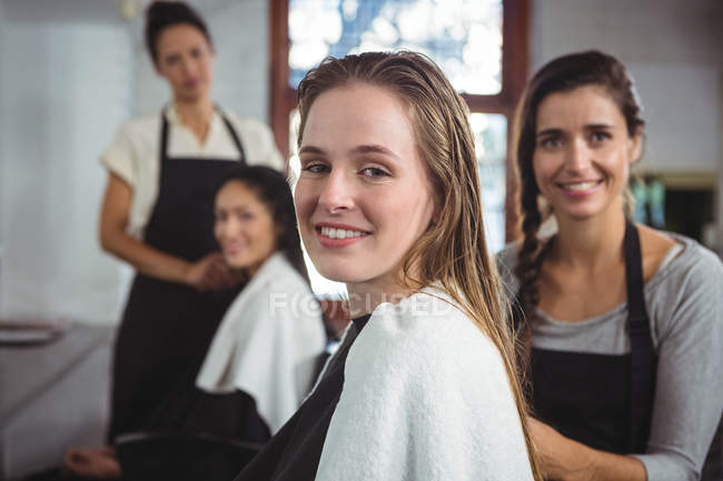 Retrato de cabeleireiros sorridentes trabalhando em clientes no salão de cabeleireiro — Fotografia de Stock