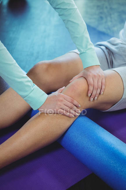 Cropped image of female physiotherapist giving physical therapy to knee of male patient in clinic — Stock Photo