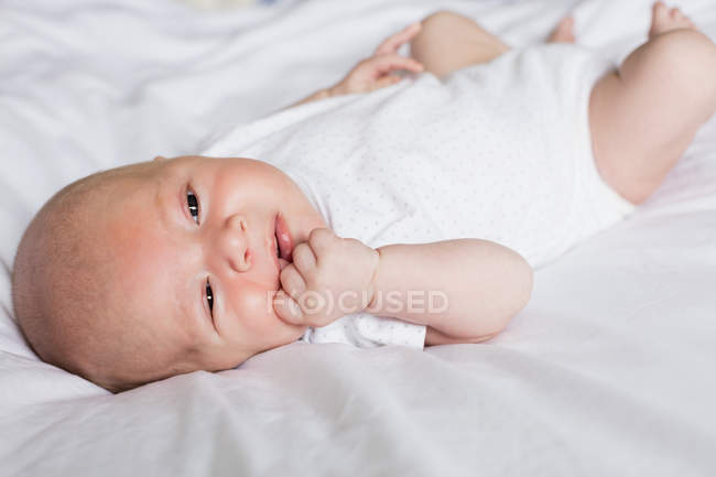 Nahaufnahme eines entzückenden Babys, das zu Hause auf dem Bett liegt — Stockfoto