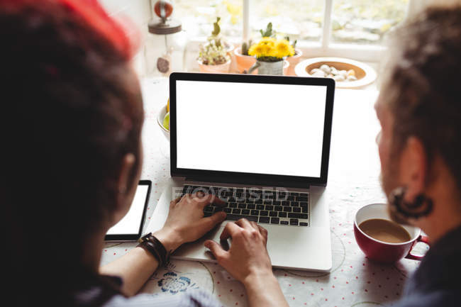 Vue grand angle du couple à l'aide d'un ordinateur portable sur la table à la maison — Photo de stock