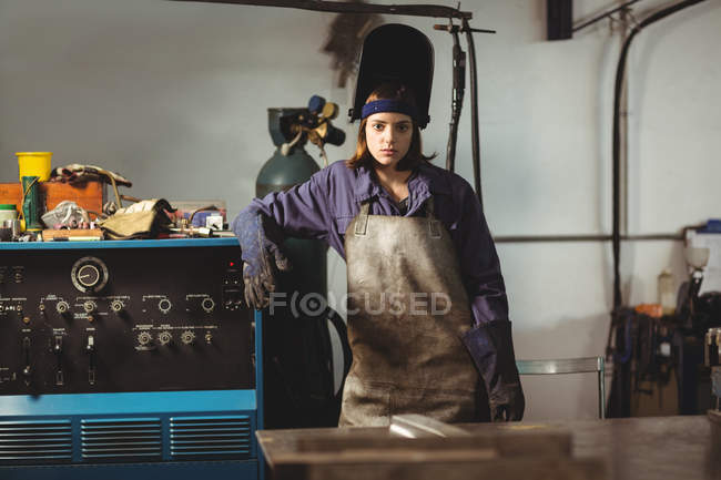 Porträt einer Schweißerin, die neben Maschine in Werkstatt steht — Stockfoto