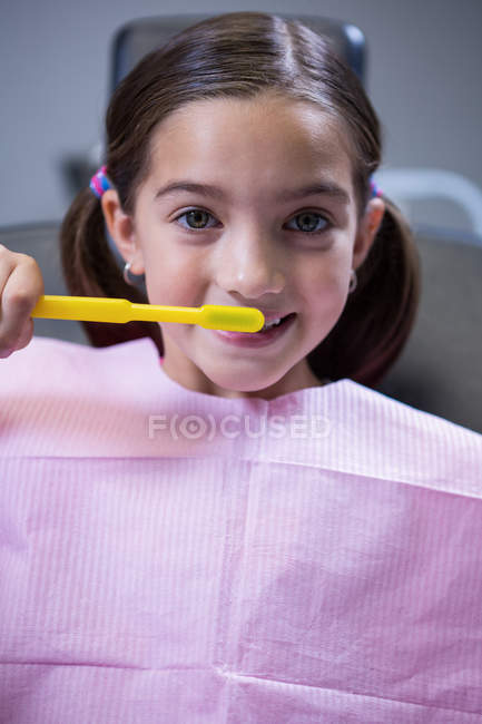 Portrait of young patient brushing teeth at dentists clinic — Stock Photo