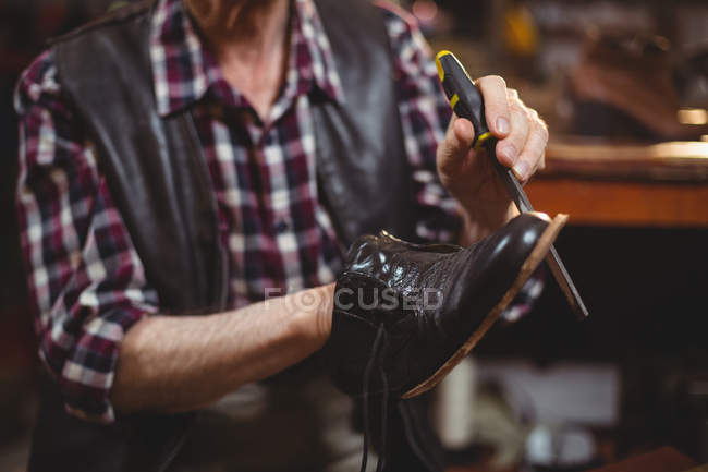 Mittelteil eines männlichen Schuhmachers, der in der Werkstatt einen Schuh repariert — Stockfoto