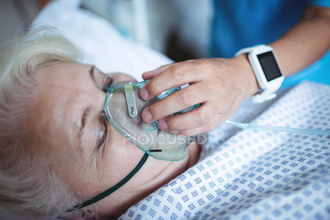 Enfermera poniendo máscara de oxígeno en el paciente en el hospital - foto de stock