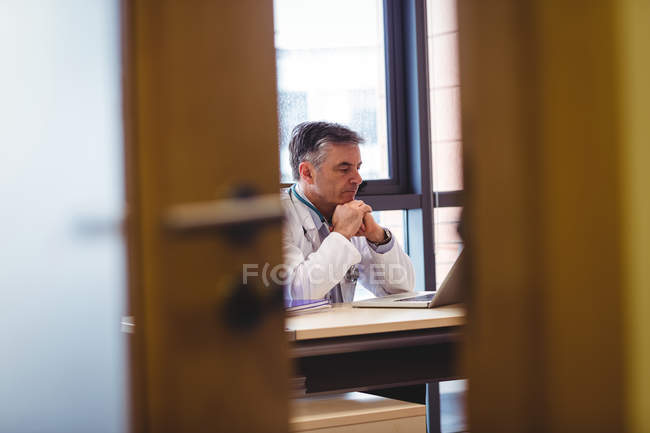 Doctor using laptop at desk at hospital — Stock Photo