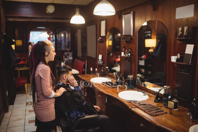 Barbeiro feminino styling cabelo do cliente na barbearia — Fotografia de Stock