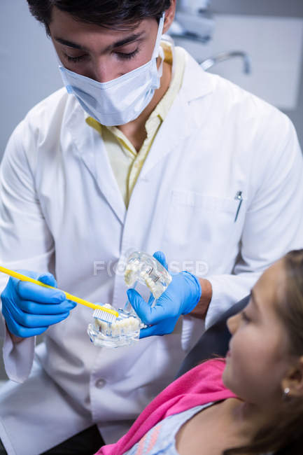 Dentist explaining mouth model to young patient at dental clinic — Stock Photo