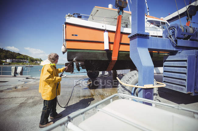 Mann reinigt Boot mit Hochdruckreiniger an sonnigem Tag — Stockfoto