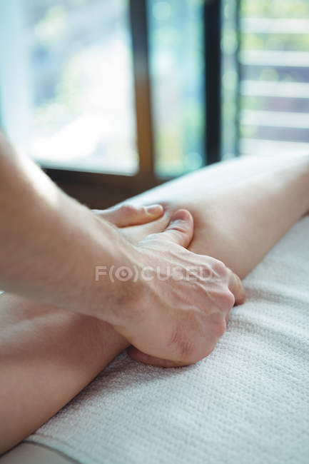 Обрезанный образ физиотерапевта, проводящего физиотерапию ноги пациентки в клинике — стоковое фото