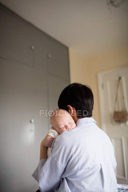 Rückansicht einer Mutter, die ihr schlafendes Baby zu Hause hält — Stockfoto