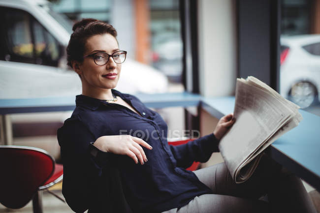 Portrait of businesswoman holding newspaper in cafe — Stock Photo