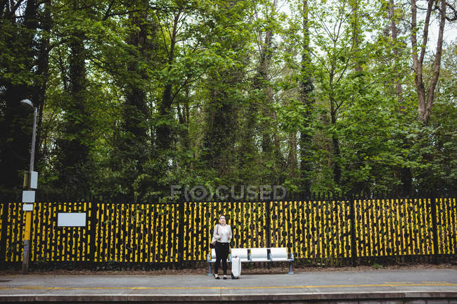 Mujer contra árboles en la plataforma de la estación de ferrocarril - foto de stock