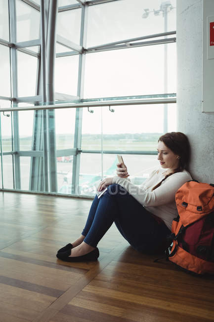 Donna che ascolta musica sul cellulare seduta in sala d'attesa — Foto stock