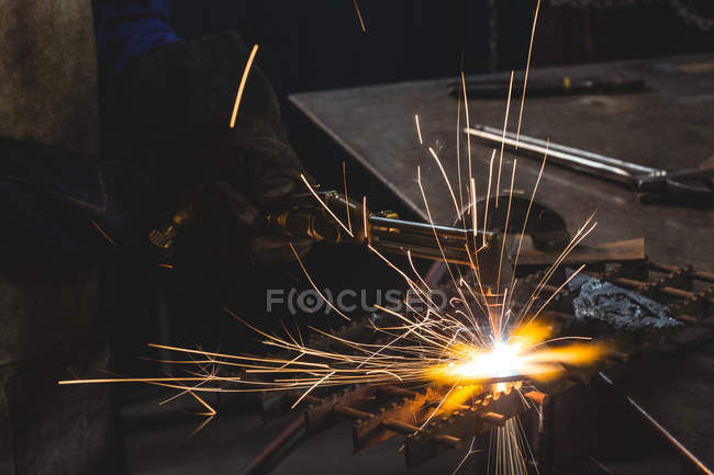 Schweißerin arbeitet in der Werkstatt an einem Metallstück — Stockfoto