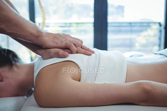 Physiothérapeute masculine donnant massage du dos à une patiente en clinique — Photo de stock