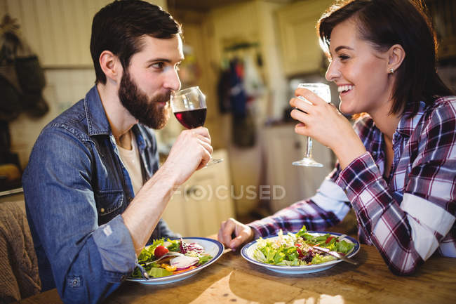 Pareja tomando vino y cenando en casa - foto de stock