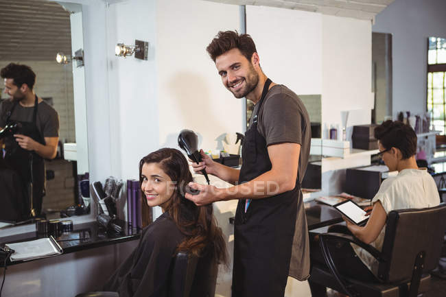 Жінка сушить волосся з фену в перукарні — стокове фото
