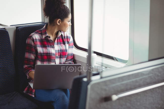 Femme regardant par la fenêtre alors qu'elle était assise dans le train — Photo de stock