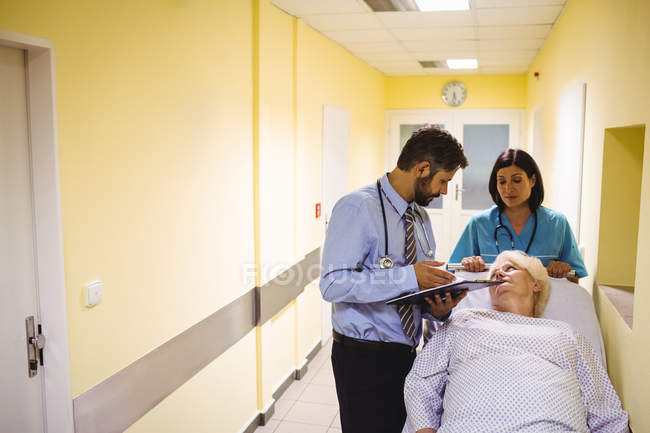 Doctor interacting over a report with senior woman in hospital — Stock Photo
