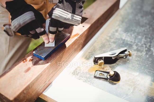 Imagem recortada de carpinteiro afiar cinzel em pedra — Fotografia de Stock