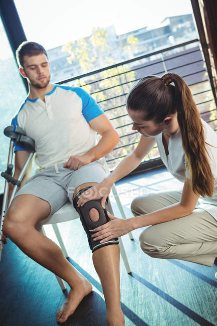 Female physiotherapist examining his patient knee in clinic — Stock Photo