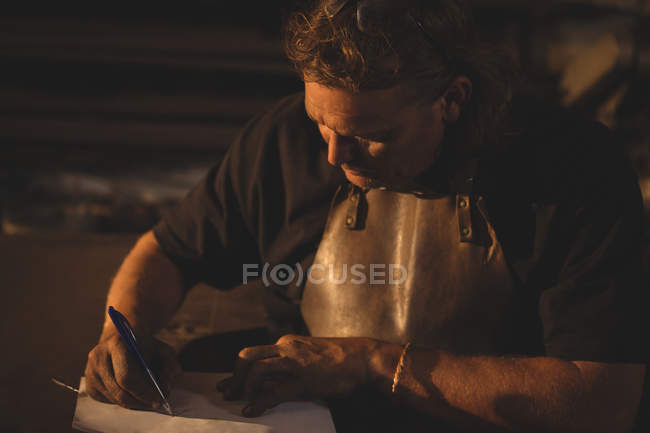 Blacksmith preparing notes at work shop — Stock Photo