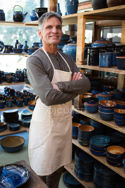 Oleiro macho feliz de pé com os braços cruzados na oficina de cerâmica — Fotografia de Stock