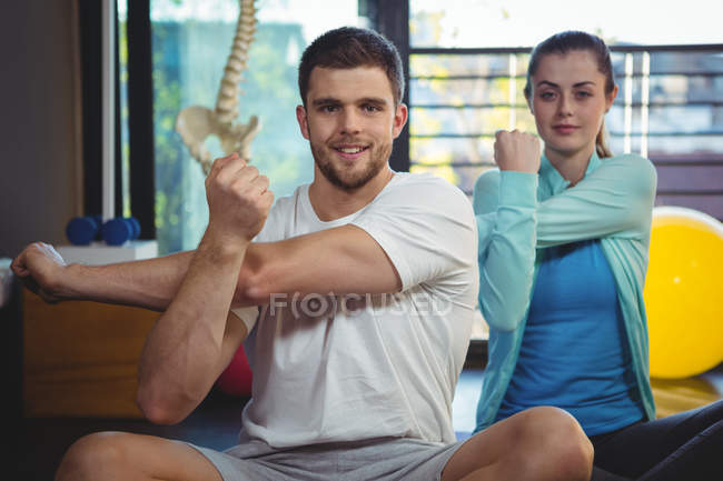 Retrato de homem e mulher realizando exercício de alongamento na clínica — Fotografia de Stock
