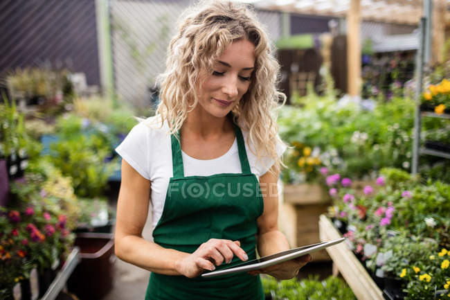 Fleuriste féminine utilisant une tablette numérique au centre de jardin — Photo de stock