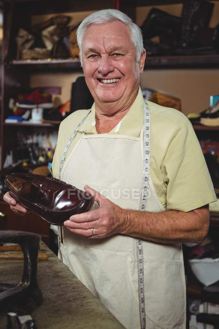 Portrait of shoemaker holding a shoe in workshop — Stock Photo