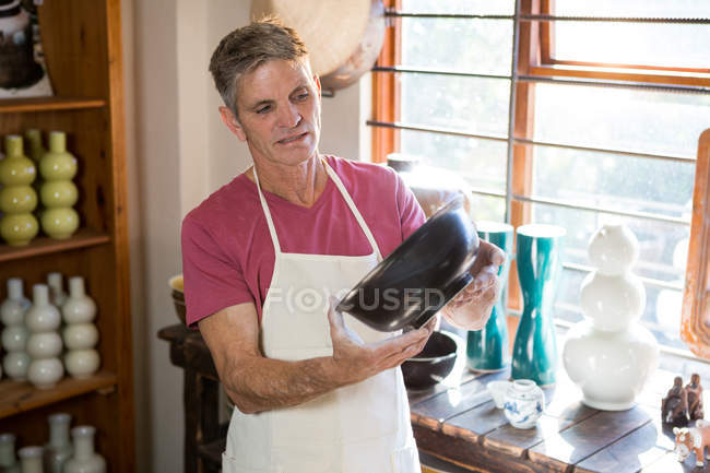 Male potter checking ceramic pot in pottery workshop — Stock Photo