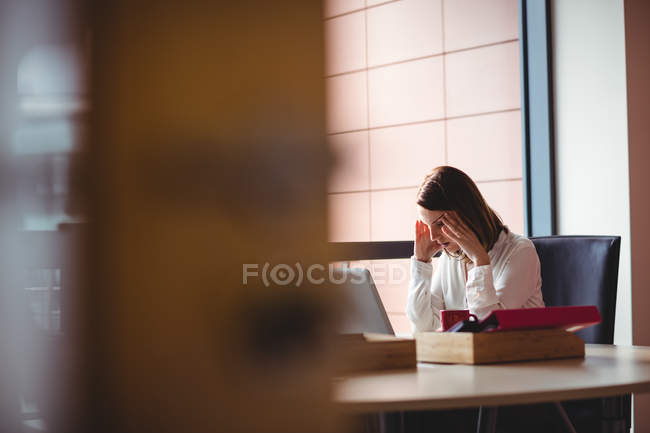 Стрессовая деловая женщина сидит за столом в офисе — стоковое фото