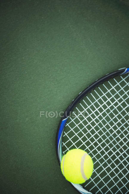 Tennis ball and racket on green ground in court — Stock Photo