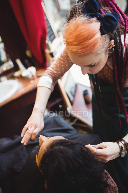 Мужчина подстригает бороду ножницами в парикмахерской — стоковое фото