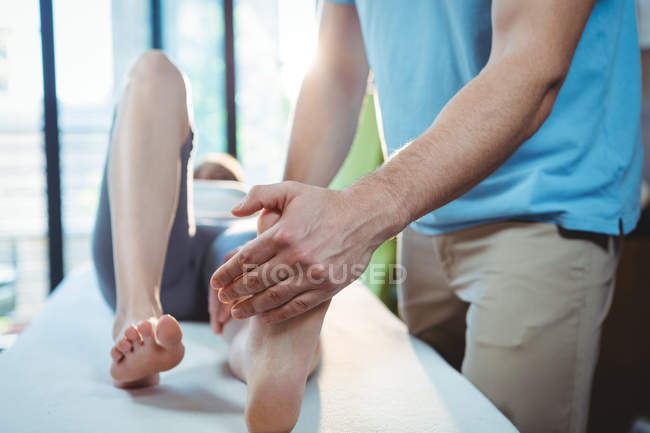 Обітнутого зображення чоловічого фізіотерапевт, даючи масаж ступень пацієнтки в клініці — стокове фото