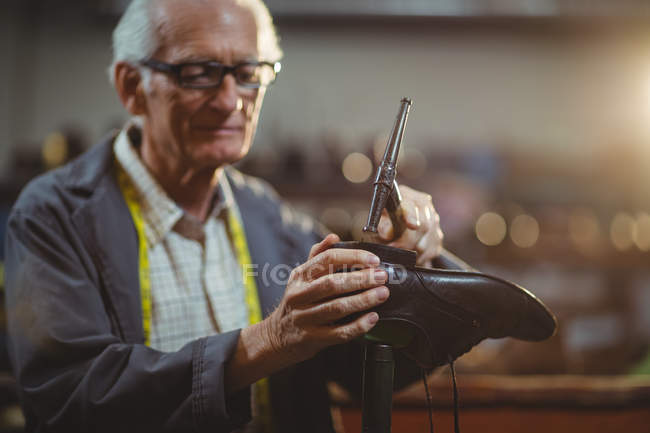 Zapatero martillando un zapato en el taller - foto de stock