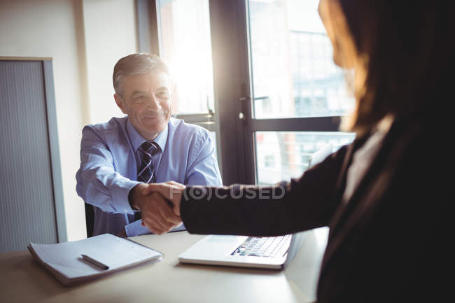 Businessman shaking hands with colleague in office — Stock Photo