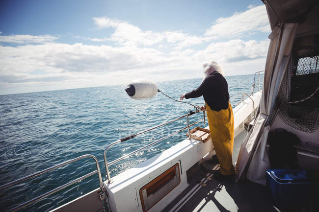 Fisherman throwing buoy into sea — Stock Photo