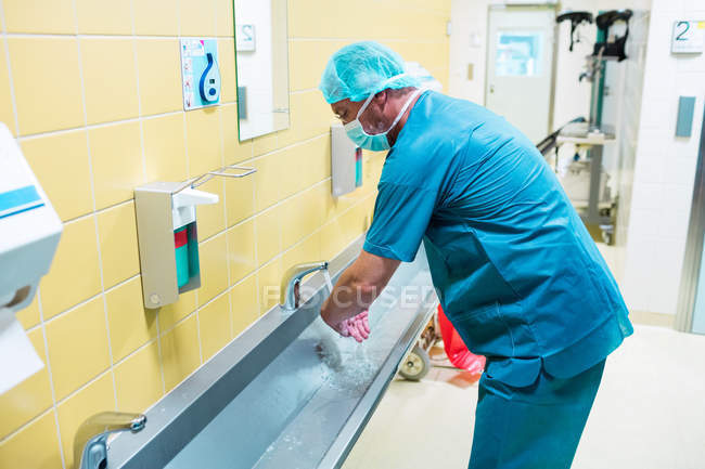Cirujano lavándose las manos en el lavabo en el hospital - foto de stock
