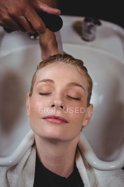 Mujer lavándose el pelo en el salón - foto de stock