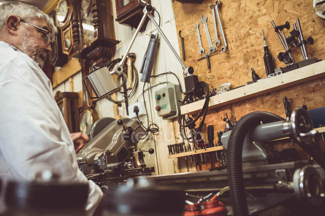 Horologist looking at a machine in the workshop — Stock Photo