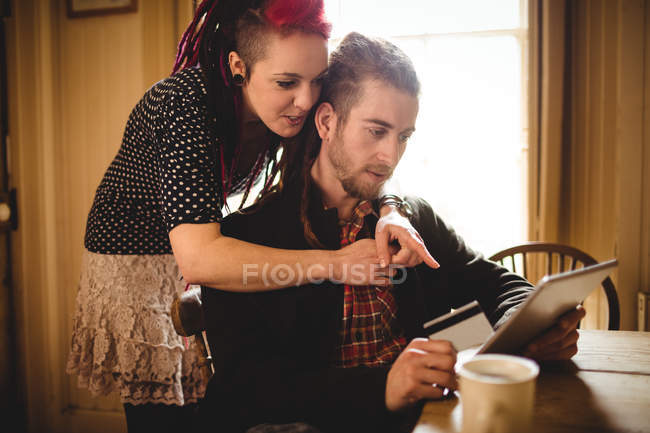 Hipster pareja utilizando la tableta para las compras en línea en casa - foto de stock