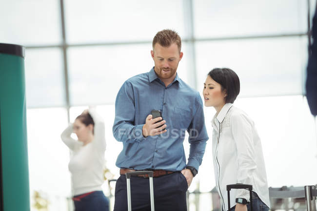 Бизнес-люди, использующие мобильный телефон в терминале аэропорта — стоковое фото