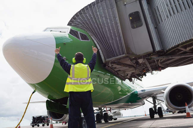 Rückansicht des Bodenpersonals am Flughafen, das Flugzeug auf die Landebahn dirigiert — Stockfoto
