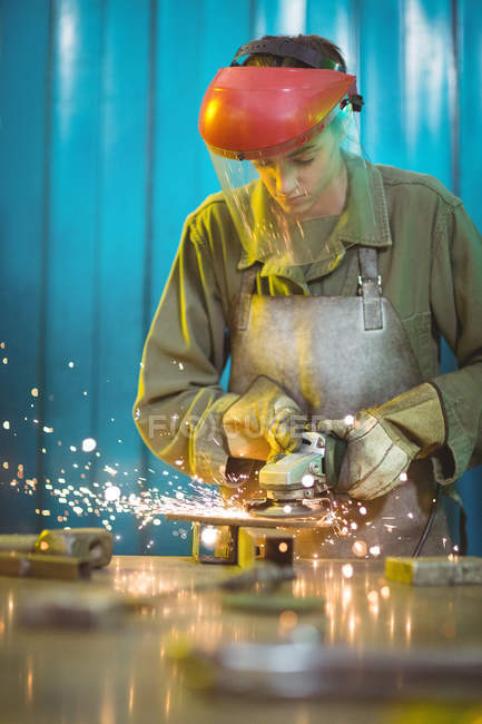 Female welder using circular saw in workshop — Stock Photo