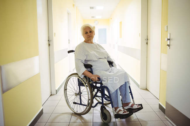 Femme âgée réfléchie assise en fauteuil roulant dans le couloir de l'hôpital — Photo de stock