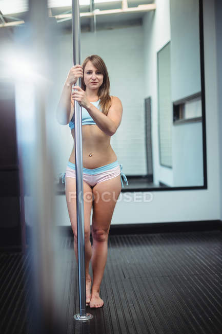 Porträt der attraktiven Pole-Tänzerin, die im Fitnessstudio die Stange hält — Stockfoto