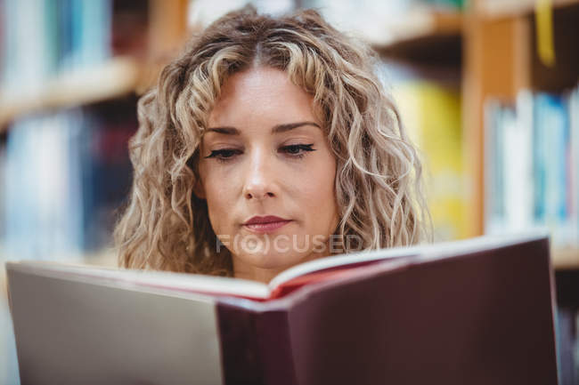 Mulher bonita leitura livro na biblioteca — Fotografia de Stock