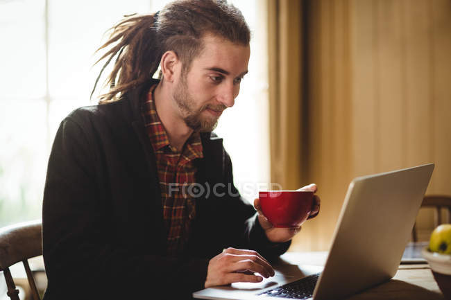 Молодий хіпстер використовує ноутбук вдома — стокове фото